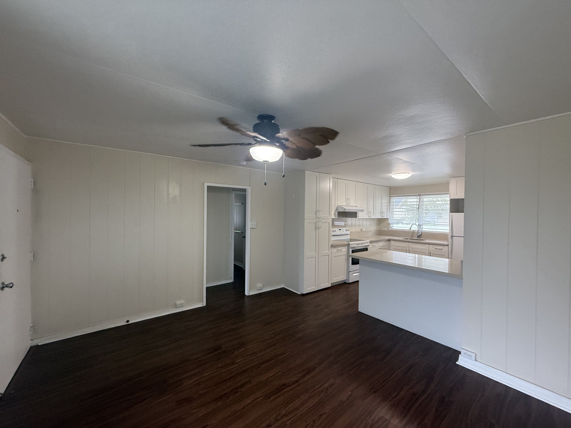 A room with a ceiling fan and wooden floors.